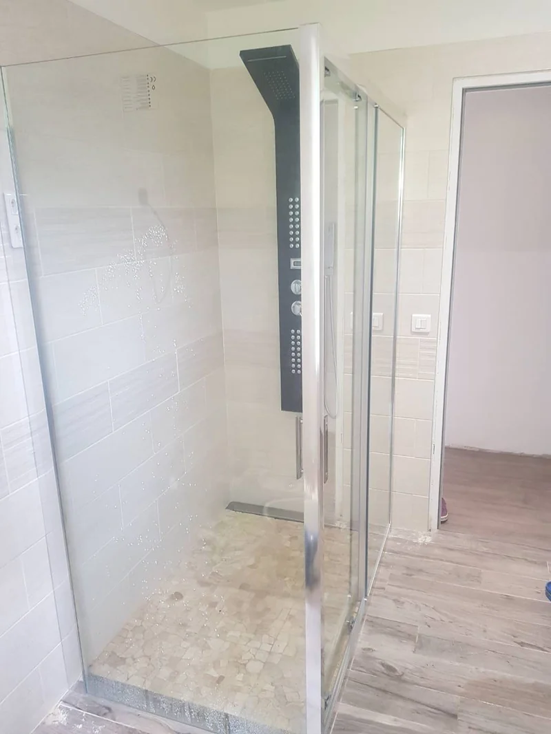Douche avec paroi vitrée, receveur en mosaïque de pierre et caniveau linéaire